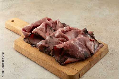 Tablou pe pânză A view of a wood board of roast beef deli slices.