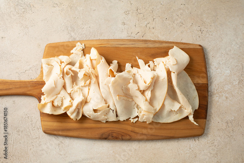 Foto A top down view of a wood board of chicken breast deli slices.