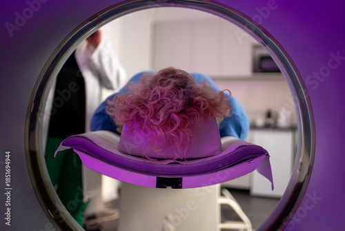 Patient undergoing MRI scan with technician in background, close-up view from inside the machine