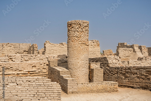 Landscape view of ancient house walls and long brick well in archaeological ruins of UNESCO World Heritage Mohenjo-Daro, Larkana, Sindh, Pakistan