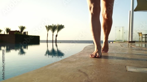 Woman walking along the edge of a swimming pool on vacation