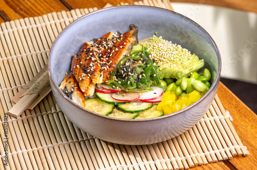 Healthy Poke bowl with eel on wooden background.