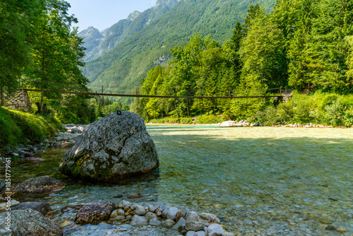 Serene Soca Valley Hike Captures Tranquil Bridge Amidst Lush Alpine Waters and Mountain Majesty