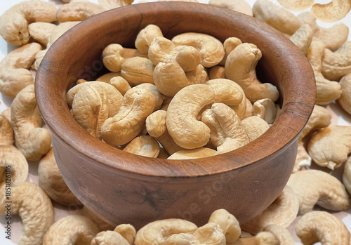 Cashews in a cup. Full bowl of cashew and some around it. Backdrop of premium cashews.
