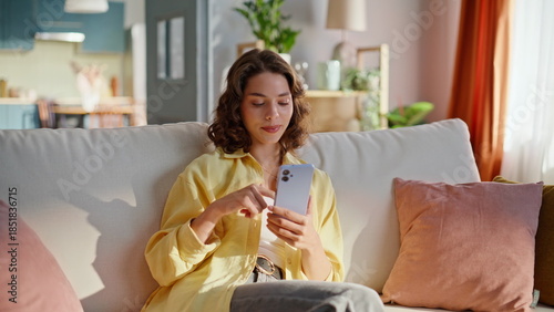 Slika na platnu Relaxed girl scrolling cellphone at couch