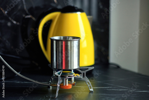 Portable gas stove and metal pot on black countertop during blackout