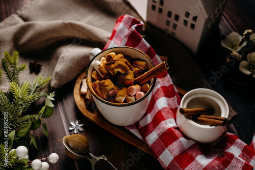 Cozy winter snack tray with cookies and hot drink on red checkered textile. Warm holiday food styling and home comfort atmosphere.