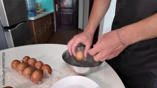Man washes chicken eggs in a metal bowl