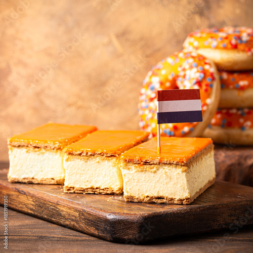 Glazed orange tompouce and donuts dessert with Dutch event Kings day in background. National holiday Koningsdag on 27 April in the Netherlands. Holland culture concept with copy space