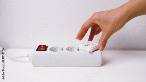 Close-up of female hand plugging a plug into a multiple socket