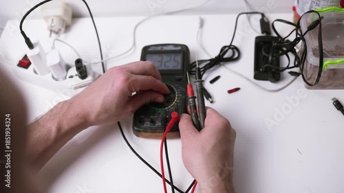 Close up on hands of caucasian man electrician using multimeter working on the plug electric or extension power strip, electric socket.