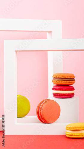 Colorful macarons arranged in white frames on a vibrant pink background with playful composition