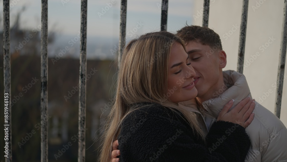 Obraz premium A young couple embraces affectionately in Paris France standing behind iron railings The image conveys love intimacy and connection in an urban setting suitable for travel lifestyle or relationship co