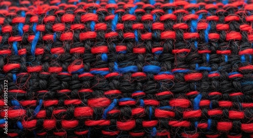 Close up macro shot of a woven textile fabric texture featuring a pattern of red, black, and blue thread