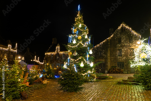 Détail d’une rue pavée du village de Locronan en Bretagne illuminée pour Noël, décorations lumineuses et façades en pierre dans une ambiance nocturne calme et chaleureuse.