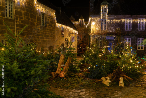 Façades en pierre et décorations lumineuses dans une rue du village de Locronan en Bretagne à l’occasion des fêtes de Noël, ambiance nocturne calme et authentique.