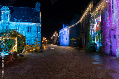 Rue pavée du village de Locronan en Bretagne décorée pour les fêtes de Noël, façades en pierre illuminées et projection festive créant une ambiance nocturne chaleureuse et authentique.