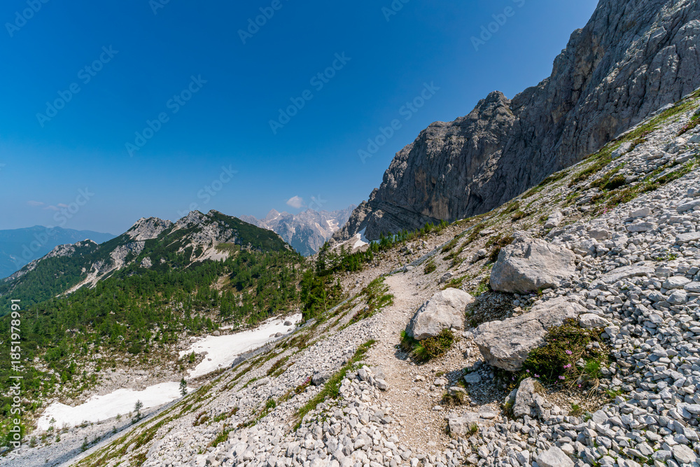 Fototapeta premium Majestic Trails of Vrsic Pass Unveiling Soca Valleys Dramatic Alpine Grandeur Under Clear Skies