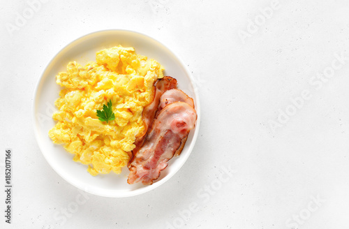 Scrambled eggs and fried bacon on plate