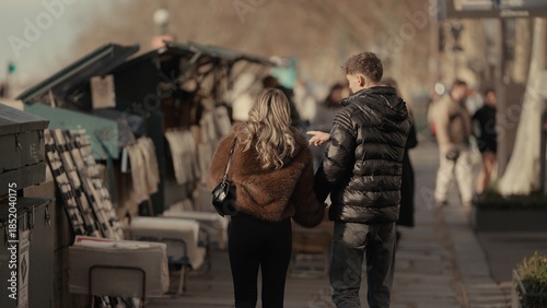 Fotografija A romantic couple walks along the Seine River in Paris France browsing the book