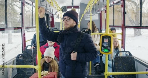 Front view of people going by public transport. Passengers on bus, boy with glasses and rucksack standing, girl with gift box sitting, old man in red jacket. Concept of routine.
