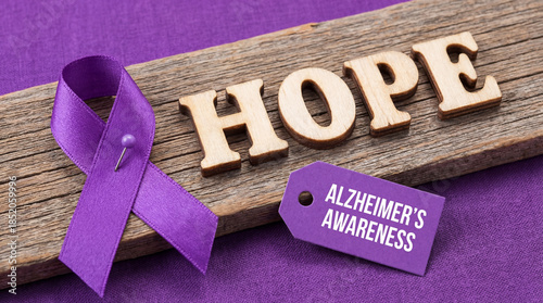 Purple ribbon pin on wood with Alzheimer's Awareness tag and Hope text. Dementia memory loss support, senior health care campaign and brain disease prevention concept on violet background