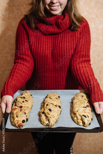 Woman holding tray with raw homemade bread dough and dried fruits before baking at home