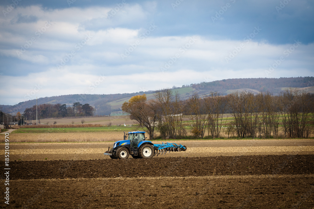 Obraz premium Tractor plowing a hilly rural field