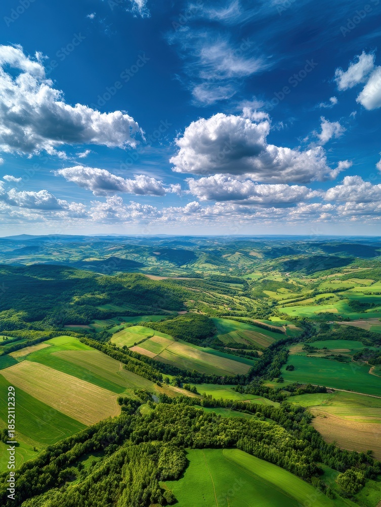 Obraz premium wide scenic aerial view of green rolling landscape under the sunny blue sky with clouds no logos no brands ar 34