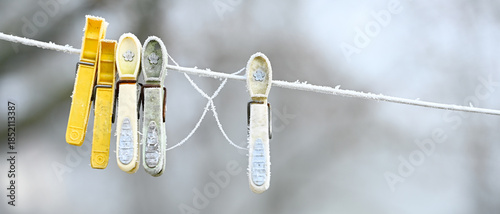 Givre sur des pinces à linge en plastique, laissés sur une corde à linge en hiver, format bannière