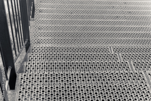 Steps covered in textured metal lead down to an inviting urban landscape at dusk