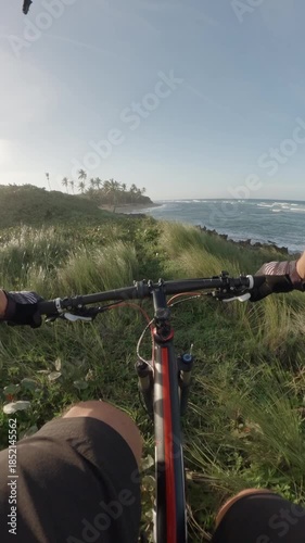 POV. Man riding on mountain bike next to ocean at sunset.	