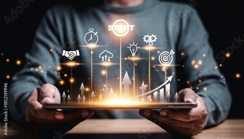 Hands hold a tablet with graphics showing progress, ideas, and goals in a dark setting, creating a modern scene of technology and innovation