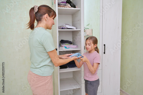 Mother and daughter sorting clothes in a cozy room.
