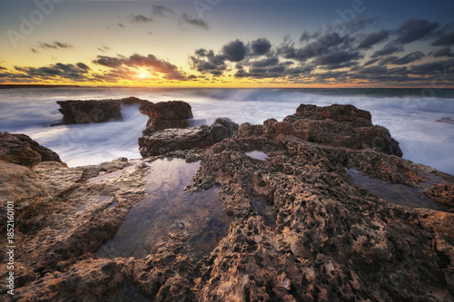 Sea waves during storm on sunset splash on stones.