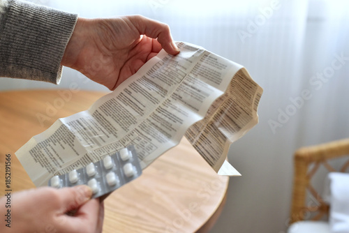 Woman holding patient information leaflet and blister with pills