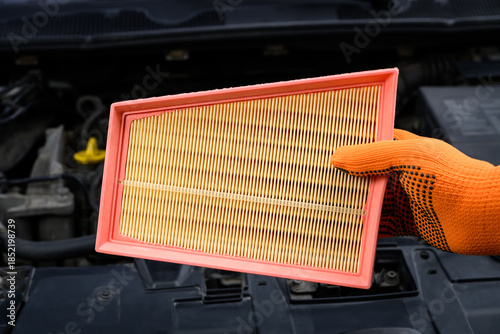 Auto mechanic holding a new air filter for car engine