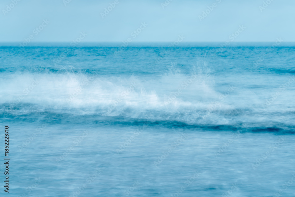 Fototapeta premium Ocean scene with a single breaking wave rendered in cool blue motion.