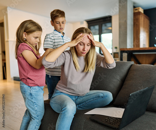 Cuadro en lienzo Portrait of a  business woman and a mother trying to work on a laptop when her little daughter and son  are playing, fooling around and interfering with her
