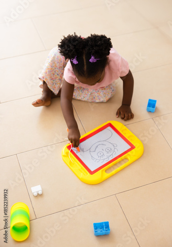 Black child drawing on magnetic board at home