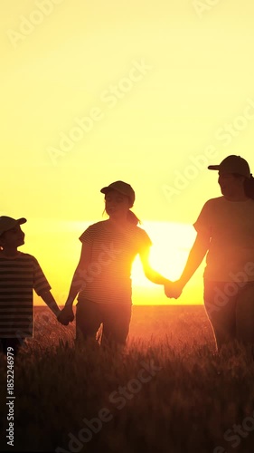 Farming family with children strolls through golden wheat field. Big farming family, group of people, a family business, teamwork. Dad mom daughter walk hand in hand. Children education, parenting
