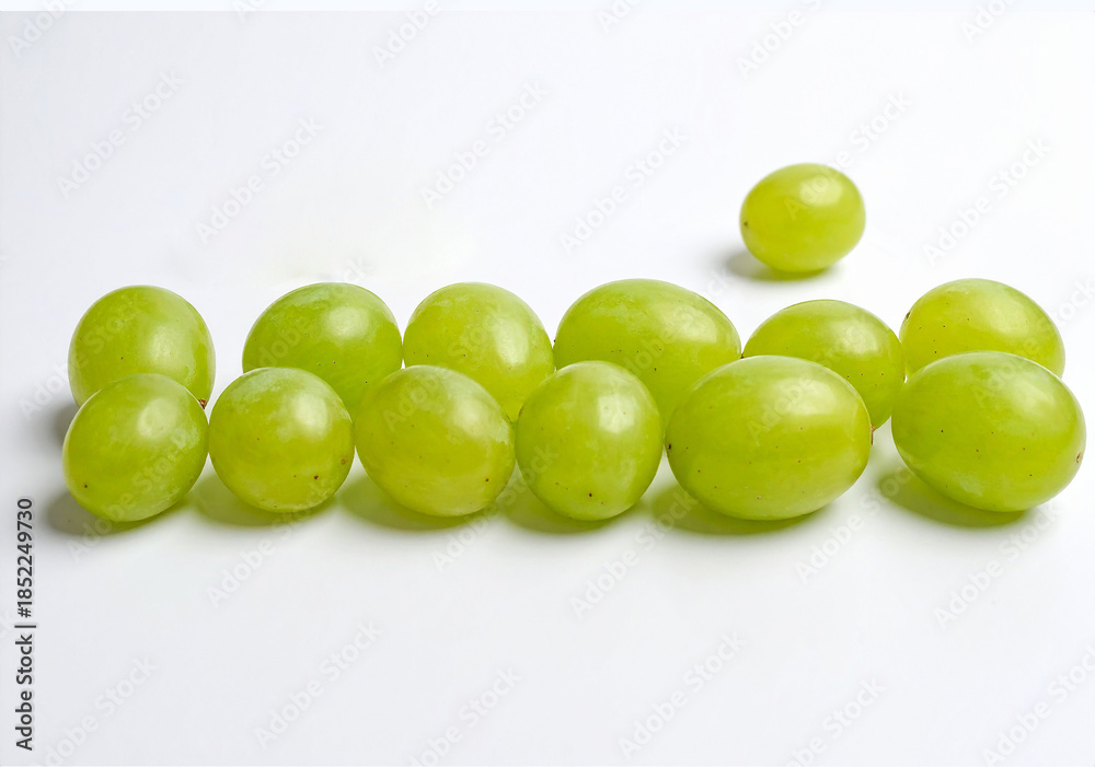 Obraz premium Doce uvas verdes frescas alineadas sobre fondo blanco, símbolo tradicional de la Nochevieja española, ritual de fin de año para atraer la buena suerte y celebrar el Año Nuevo