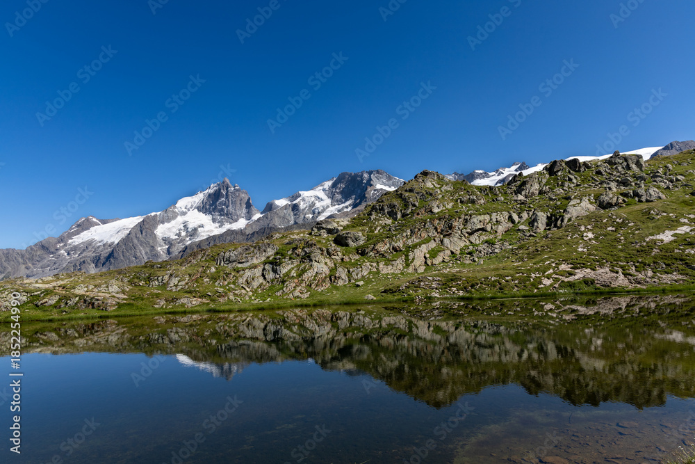 Fototapeta premium Lac Lérié with a scenic view of La Meije peak on the Emparis Plateau in the Arves Massif, Hautes-Alpes, France.