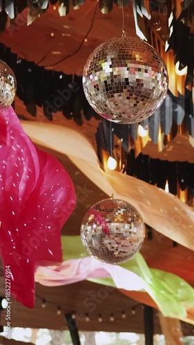 Vertical video. Disco balls hanging between colorful fabrics. Decor for a party or wedding, disco party.