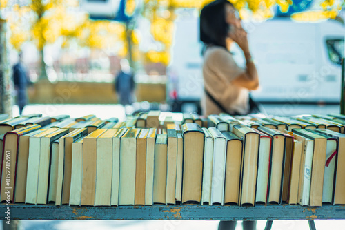 The street of Cuesta de Moyano in Madrid is shown, known for its permanent open-air book fair. Thirty bluish-grey wooden stalls sell second-hand, rare, and out-of-print books along this pedestrian