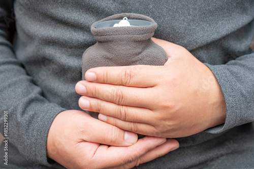 man holding a small hot water bag on the stomach
