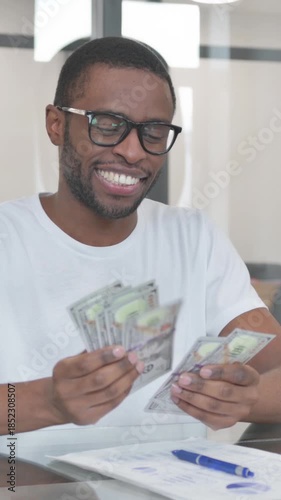 Young African Man Counting Money in Office, vertical video