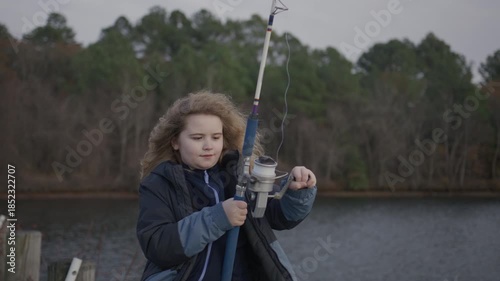 Child focused on fishing rod. Kid fishing in quiet lake. Child relaxing with fishing. Child fishing during autumn day.