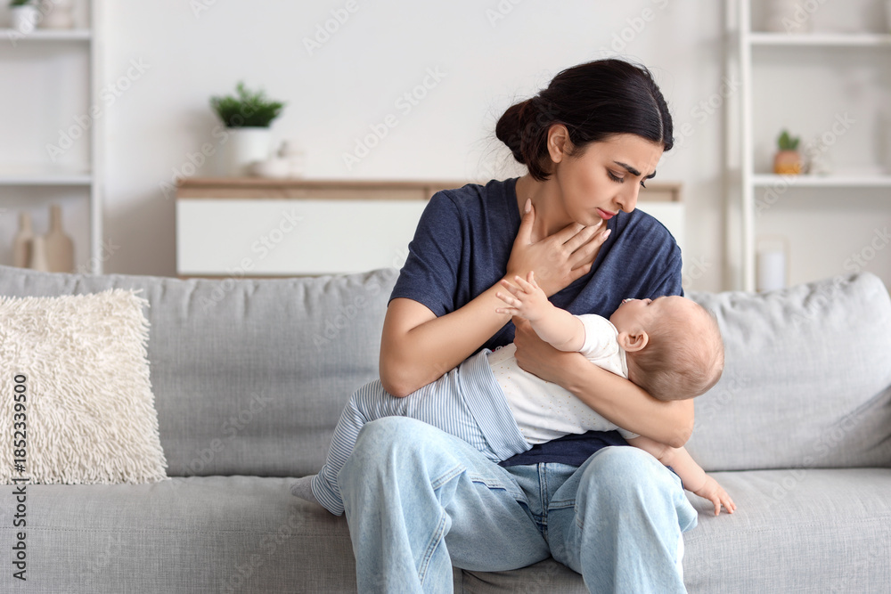 Obraz premium Young mother suffering from postnatal depression with her baby on sofa at home