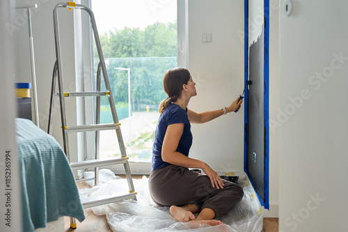 Bild auf Leinwand Woman painting interior wall with roller during home renovation at home